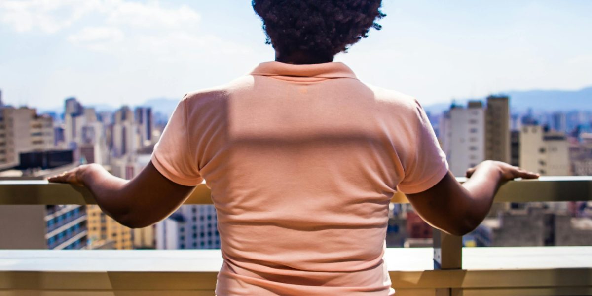 A person looks contemplatively at a cityscape, reflecting on the implications of ubiquitous surveillance technologies.