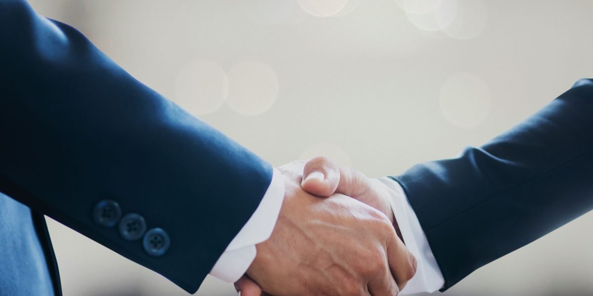 Two professionals shake hands after a successful meeting, symbolizing the partnerships fostered by funding and policy programs for tech innovation.